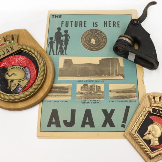 Items from Ajax Archives, including two Ajax seals, an embossing press, and an Ajax Business area brochure from the 1950s.