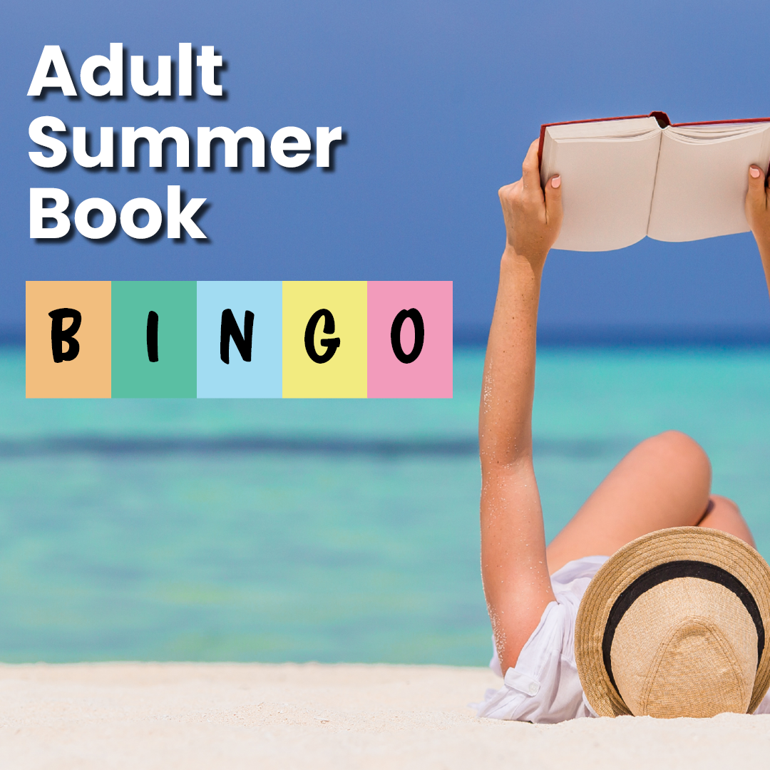 A woman reading on a beach wearing a sun hat, laying on her back with the book extended in the air. 
