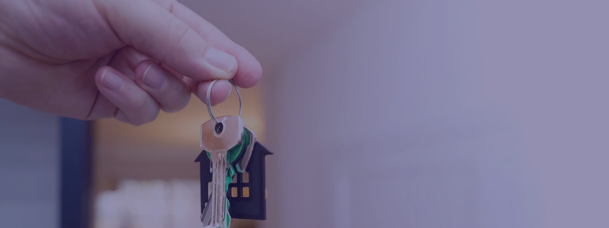 A person holding a set of keys with a house-shaped key chain.