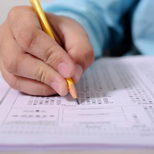 Person taking scantron test with pencil. 