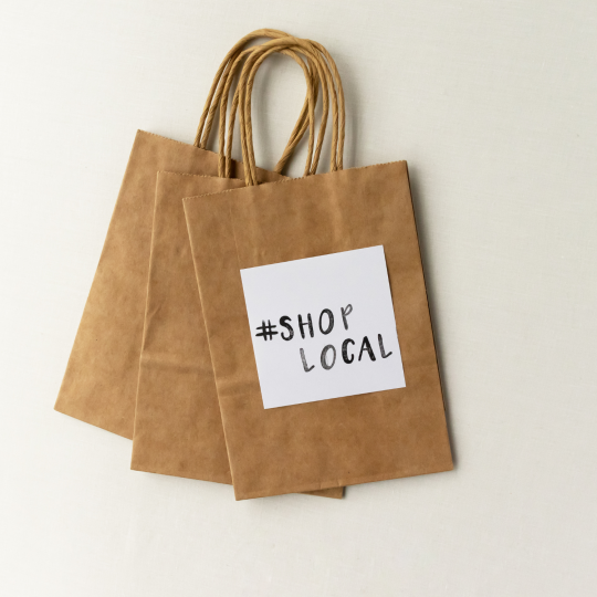 Brown paper shopping bags that read shop local. 