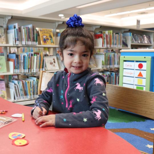 A child smiles as they colour in the McLean Branch.
